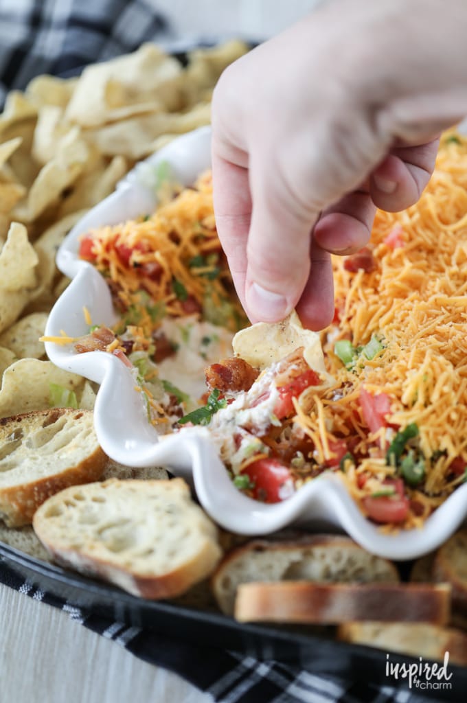 hand scooping into BLT dip with tortilla chip. 