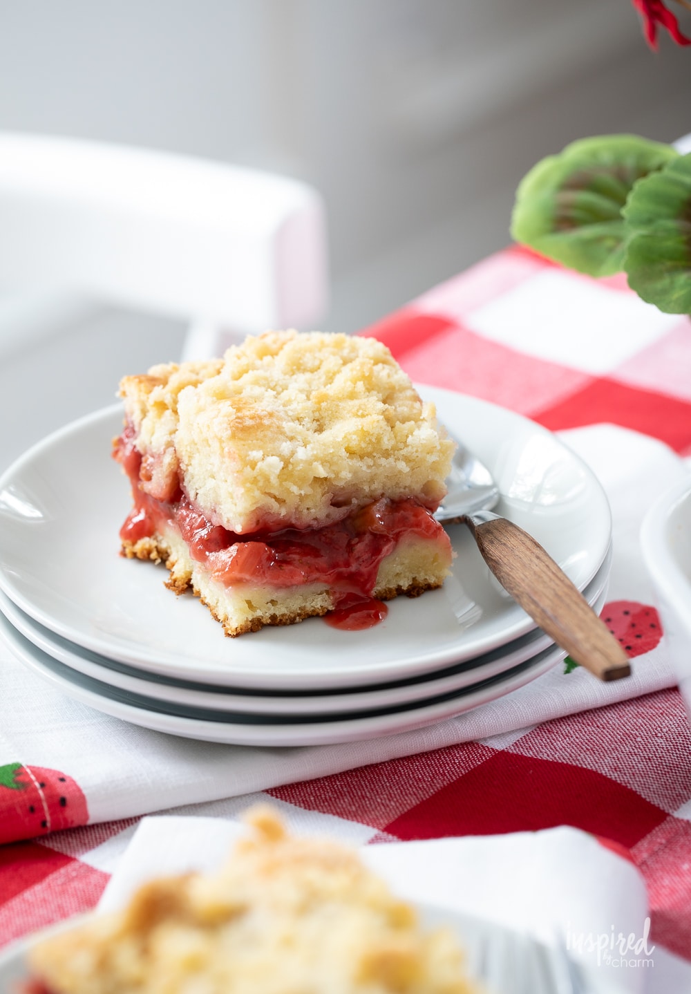 piece of strawberry rhubarb coffee cake on a stake of small white plates.