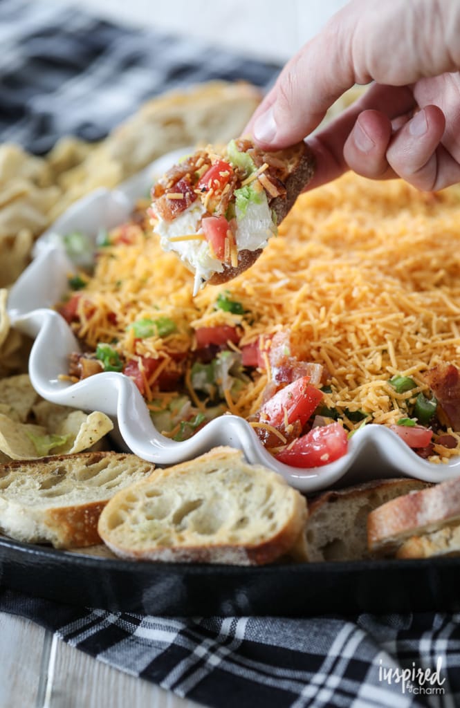 person scooping up BLT inspired dip on a piece of crusty bread