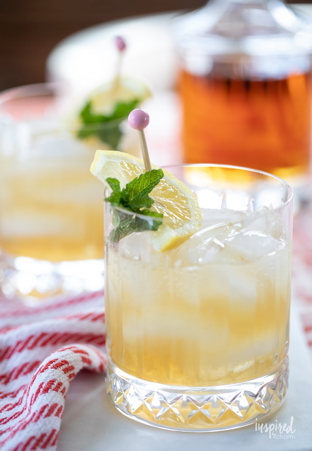 bourbon smash cocktail in rocks class with lemon wedge and mint garnish.