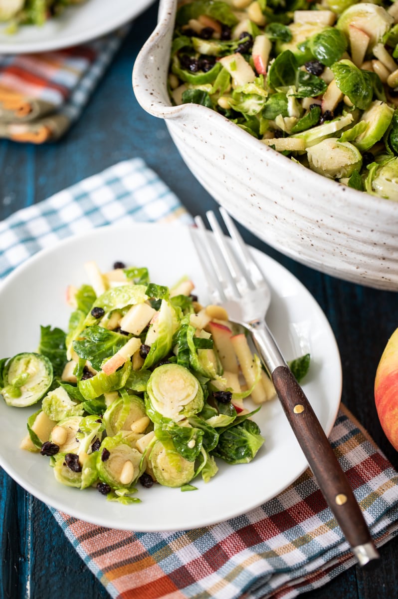 shaved Brussels sprouts salad served on a white plate with a fork.