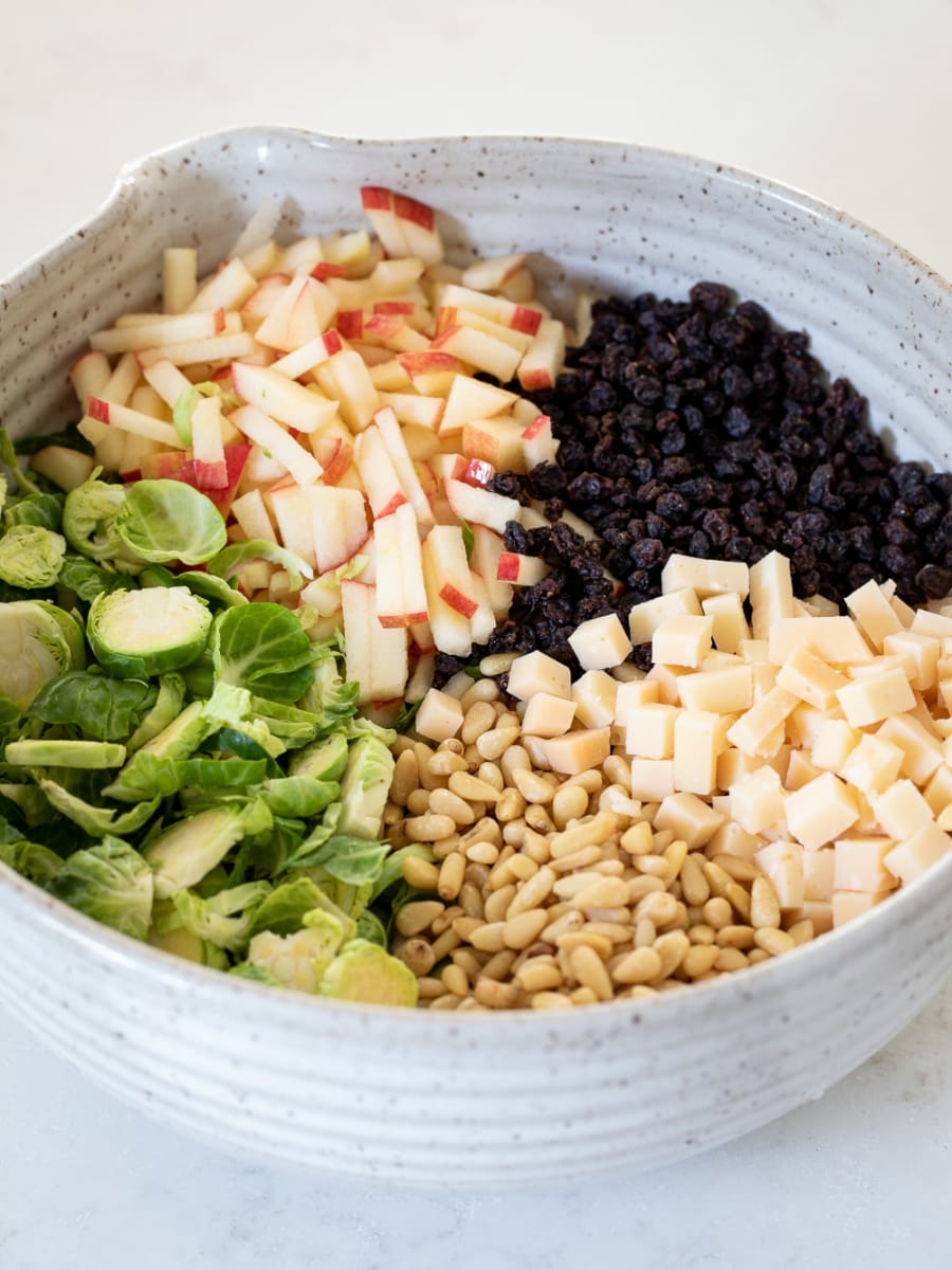 Shaved Brussels Sprout Salad ingredients divided in a large bowl.
