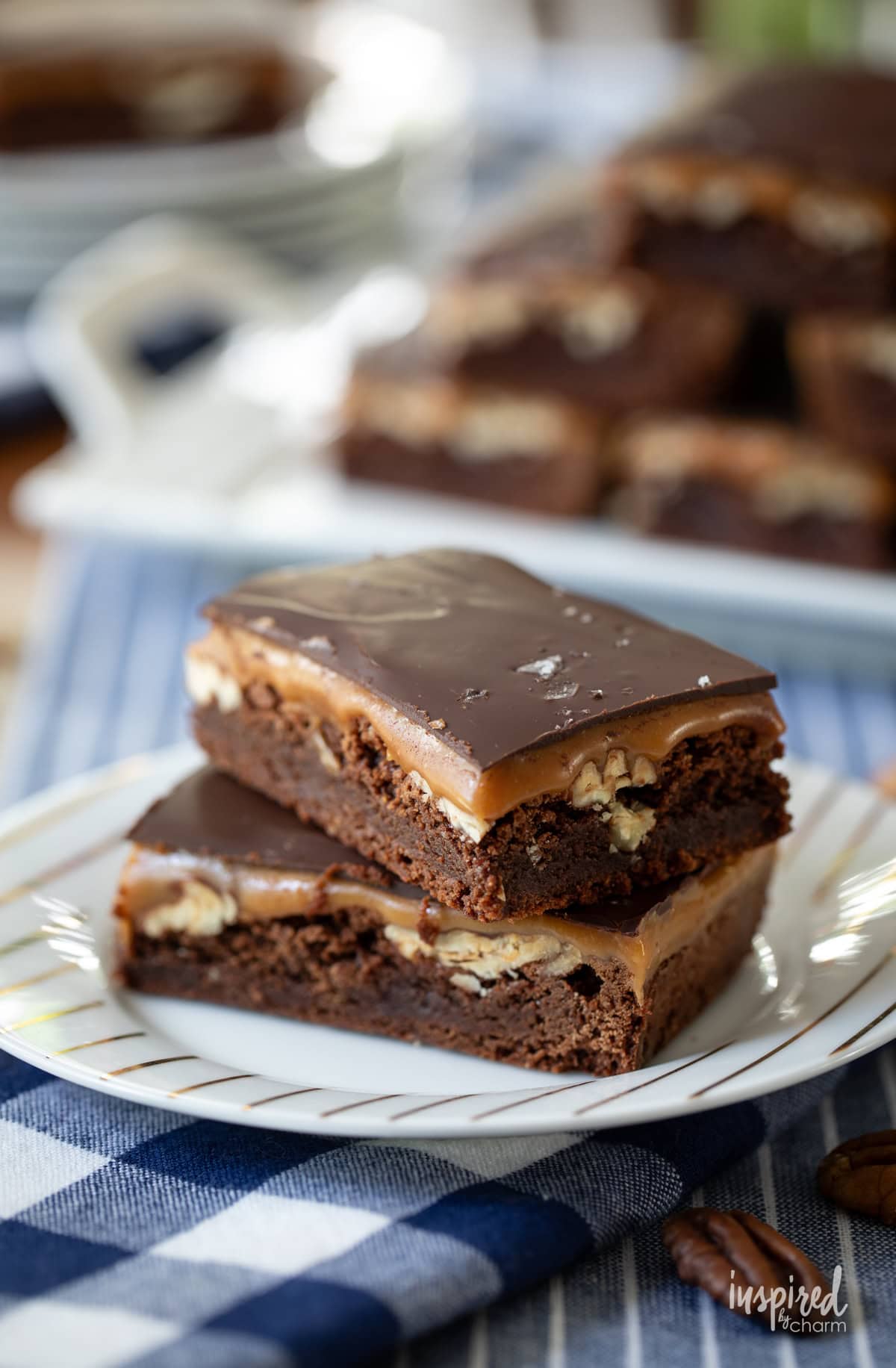 two Caramel Pecan Turtle Brownies stacked on a plate.