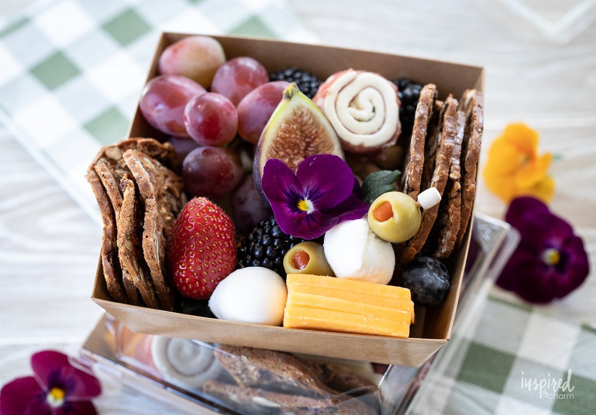 close up of a charcuterie box filled with meats, cheese, fruits, and more.