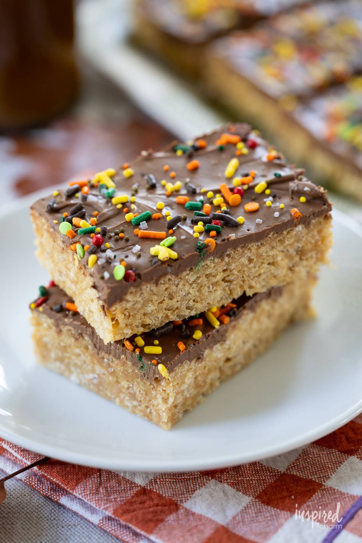 two Chocolate Peanut Butter Scotcheroos stacked on a small plate.
