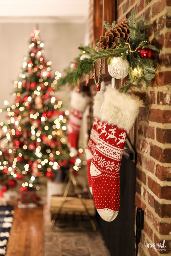 stocking hung on a mantel with a christmas tree. 