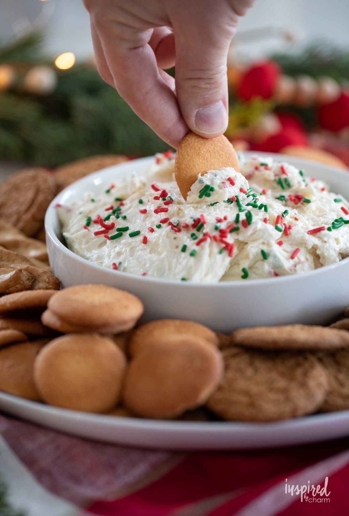 hand dipping cookie into Christmas Sugar Cookie Dip.