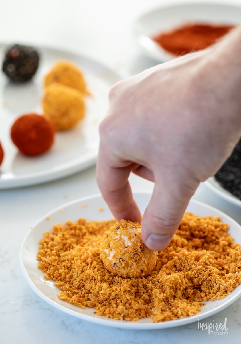 hand rolling cheese ball in crushed Doritos. 