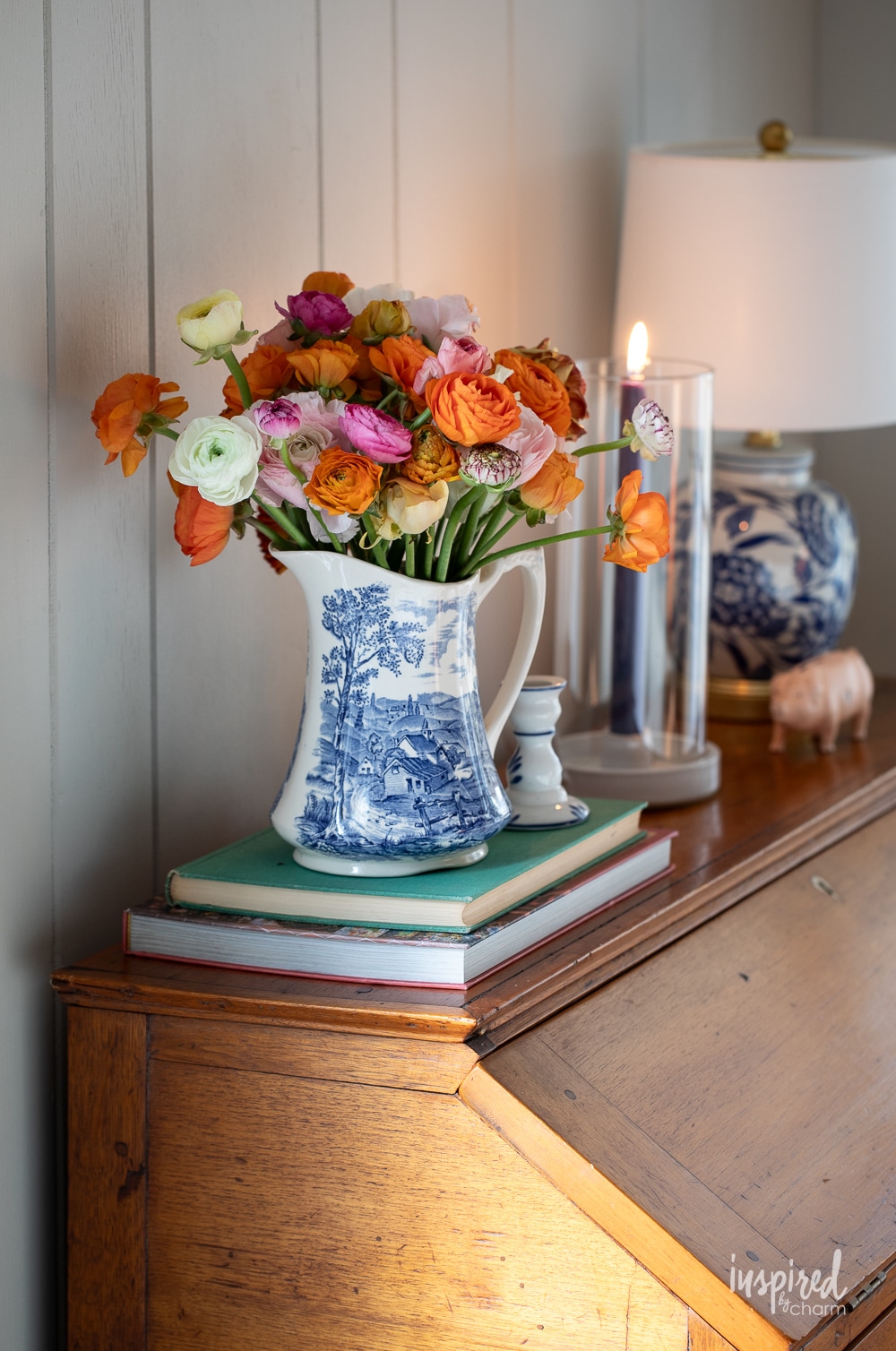 transferware pitcher filled with color ranunculus on a desk.