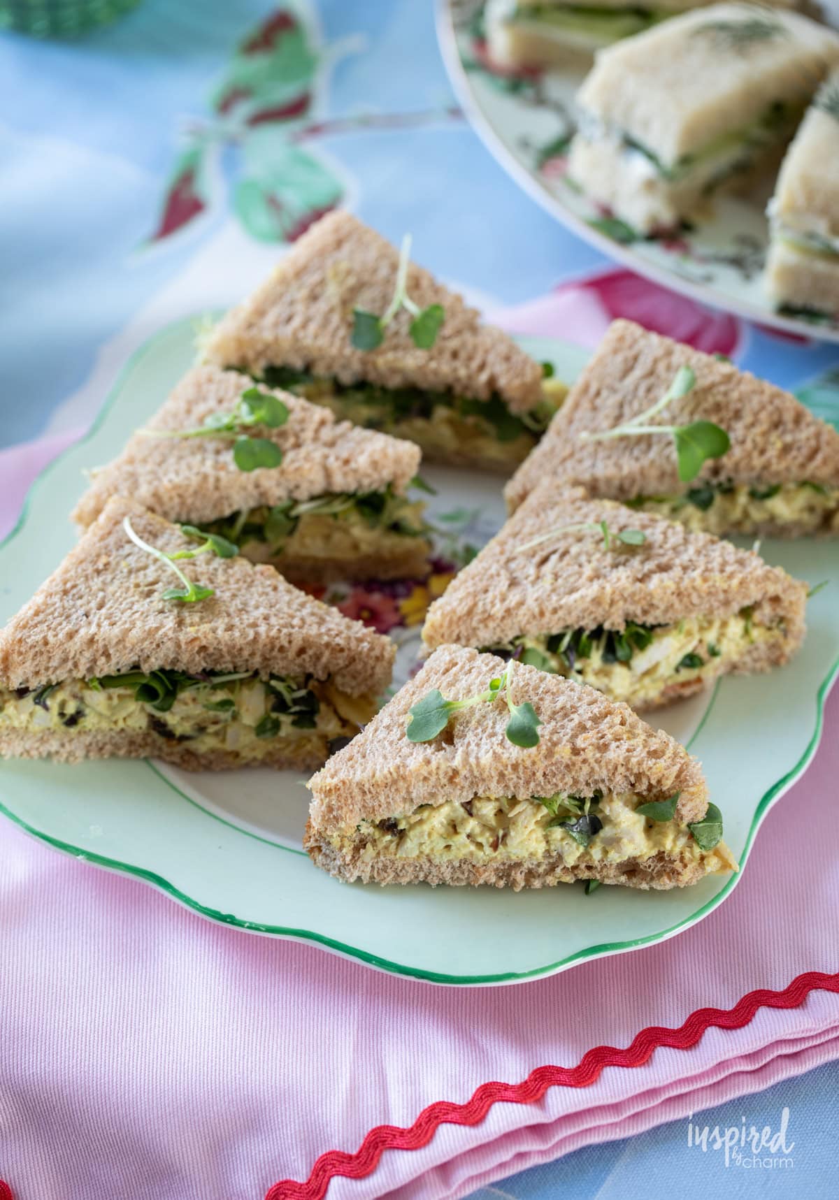 triangles of coronation chicken sandwiches on a plate.