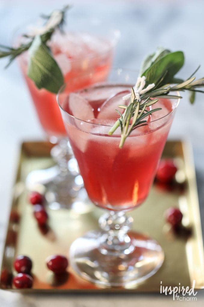 Festive Cranberry Bourbon Cocktail with fresh herb bundle garnish.