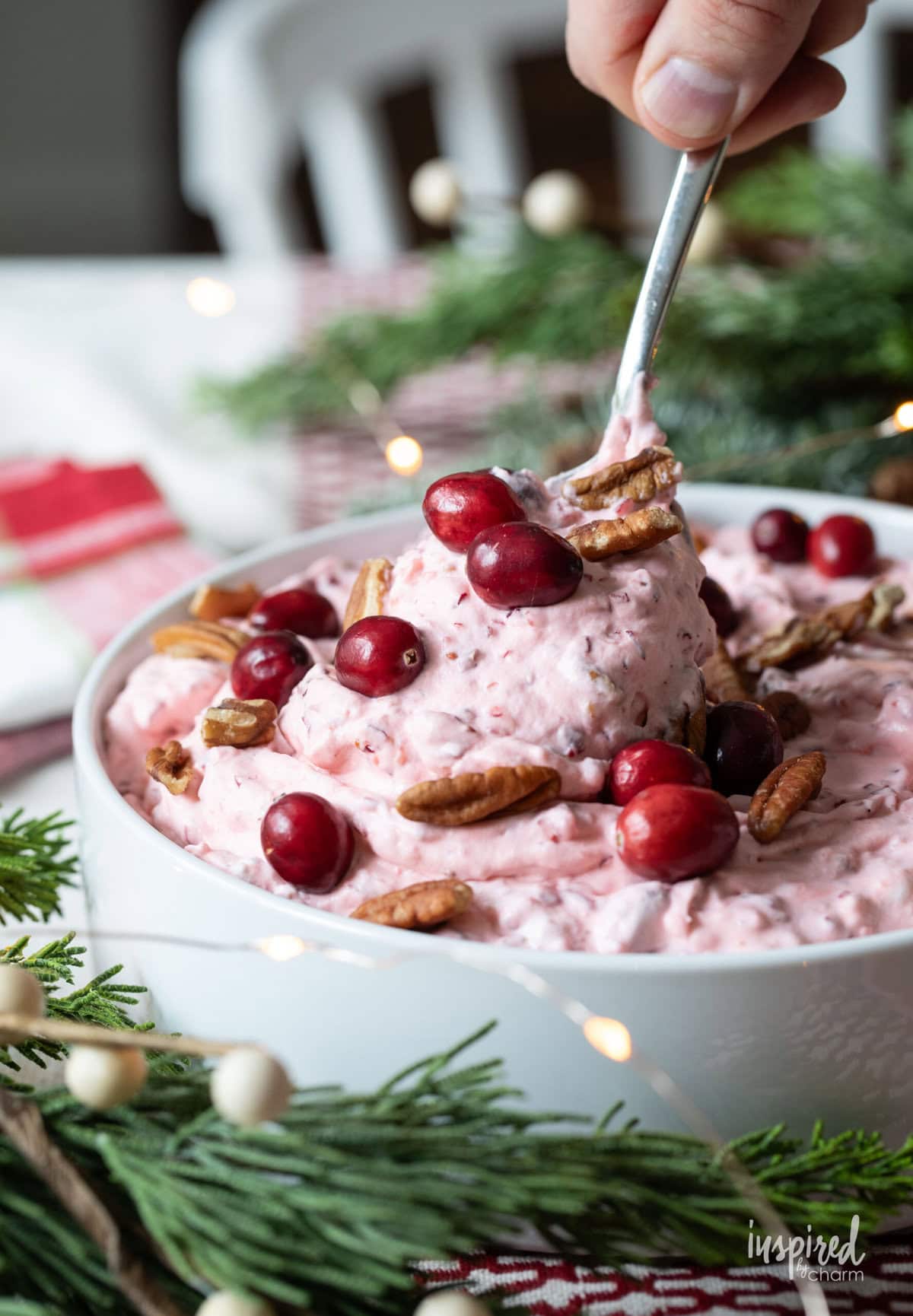hand with spoon taking a scoop of cranberry fluff salad.