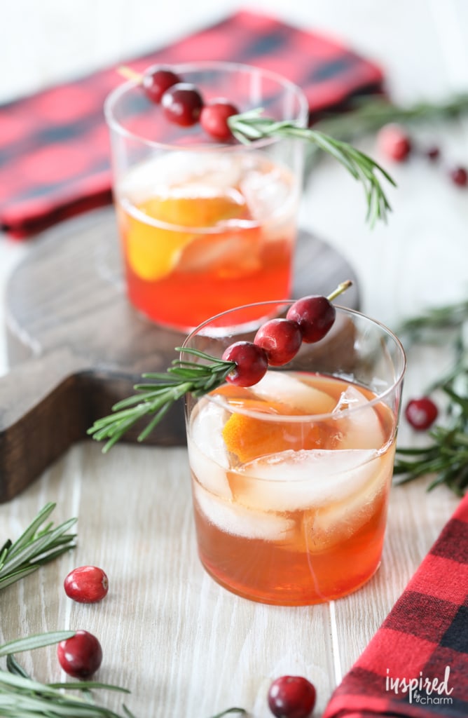two cranberry old fashioned cocktails with cranberry and rosemary garnish. 