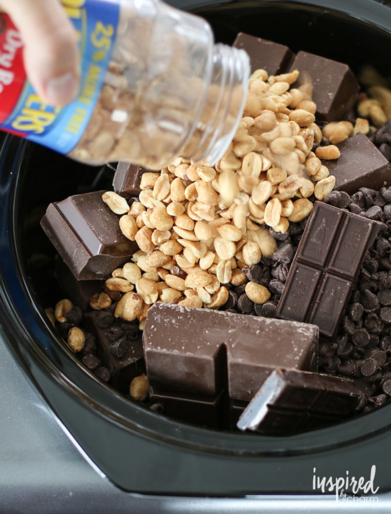 adding chocolate and peanuts to crock pot.