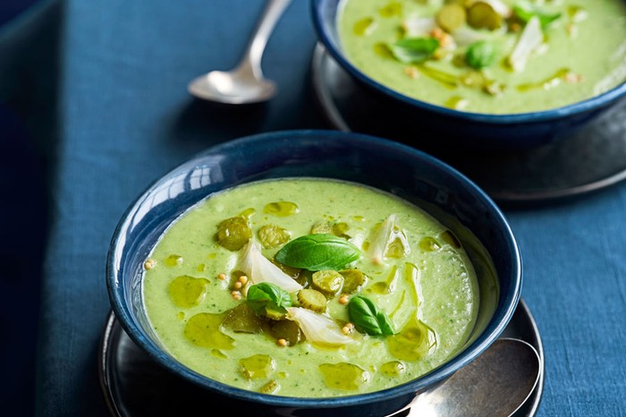 Two bowls of cucumber, cornichon and pickled onion gazpacho topped with olive oil and basil