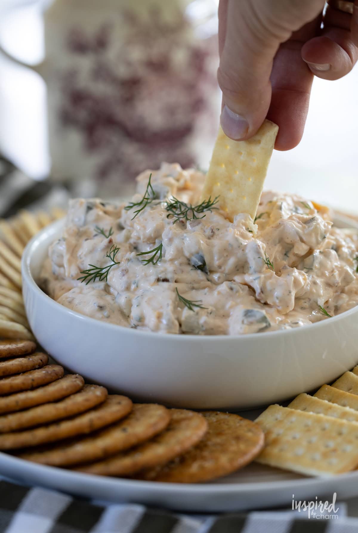 hand with cracker dipping into dill pickle dip.