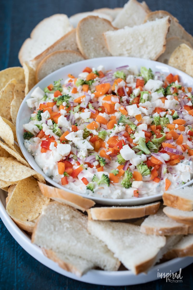 bowl of veggie pizza dip with bread and tortilla chips.