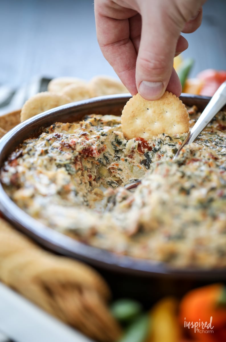 spinach artichoke tomato appetizer spread on a cracker