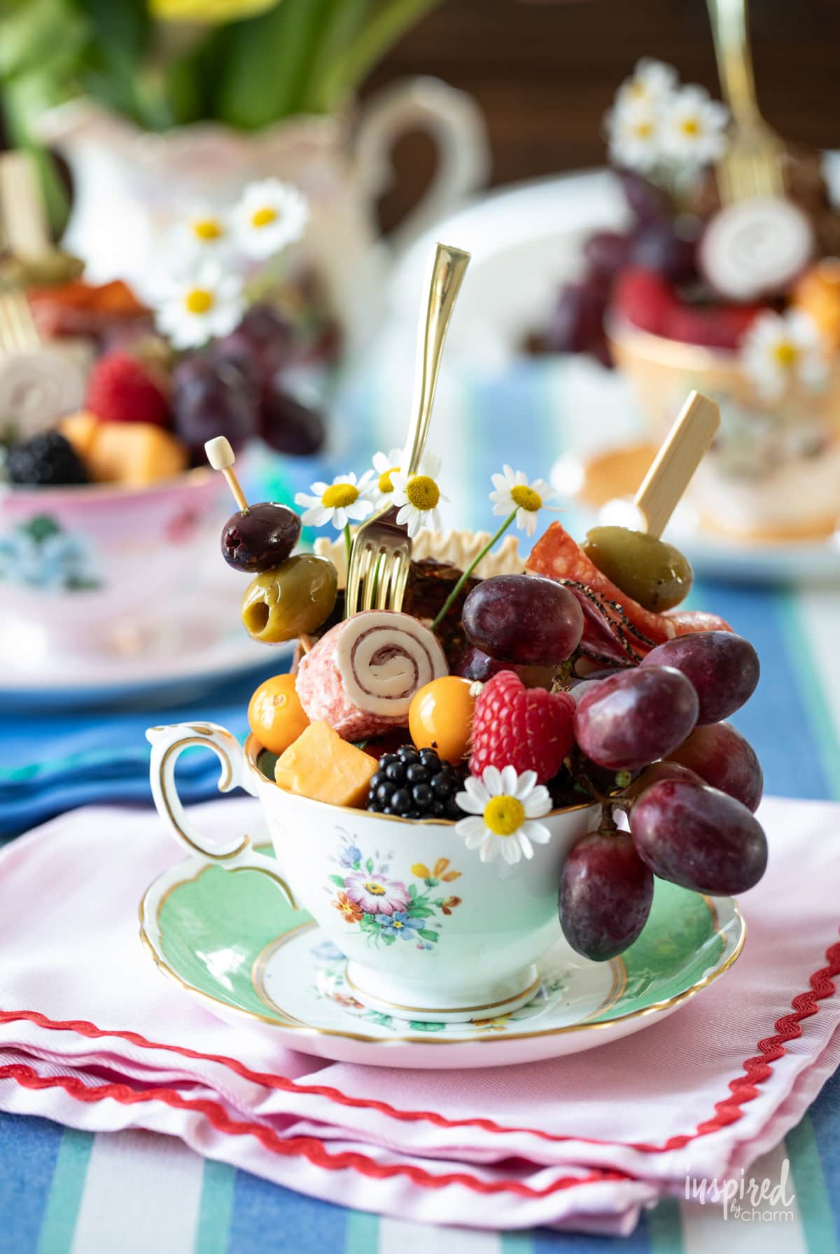 trio of teacup charcuteries filled with meats, cheese, fruit, and nuts.