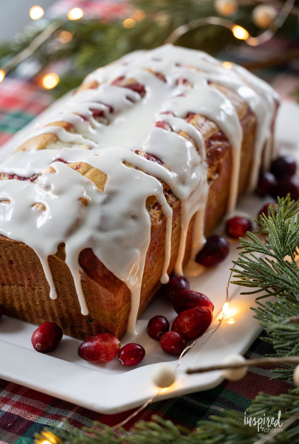 Cranberry Marble Loaf Cake with glaze on a plate with cranberries.