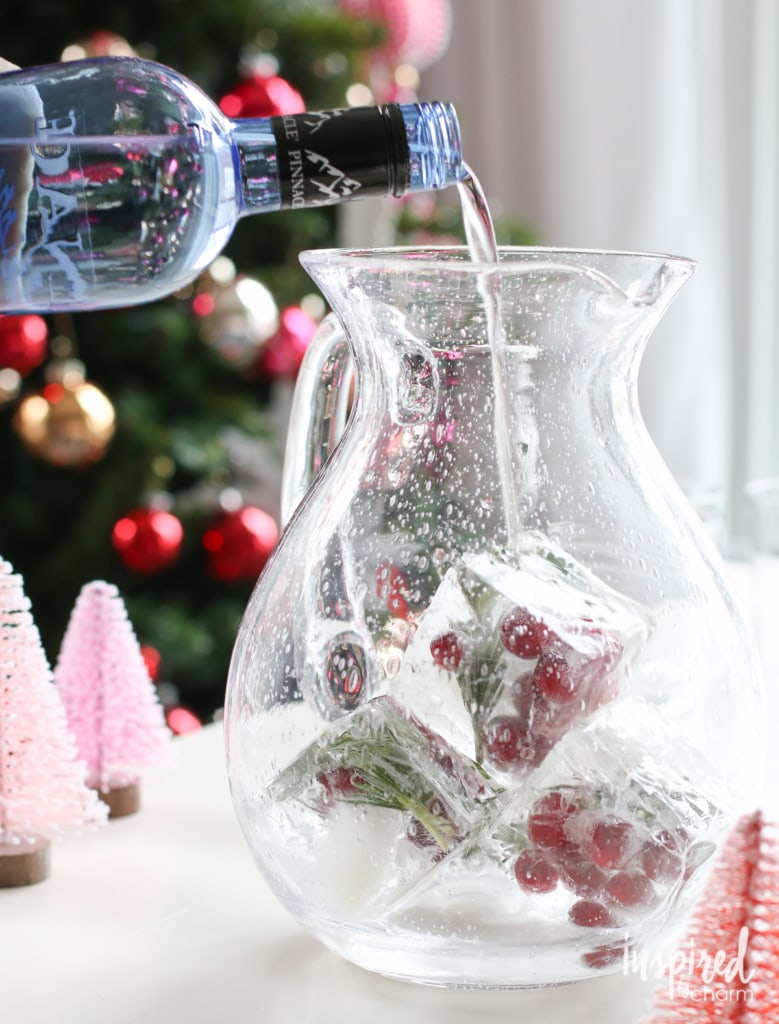 Adding whipped vodka to a pitcher filled with frozen cranberry ice cubes
