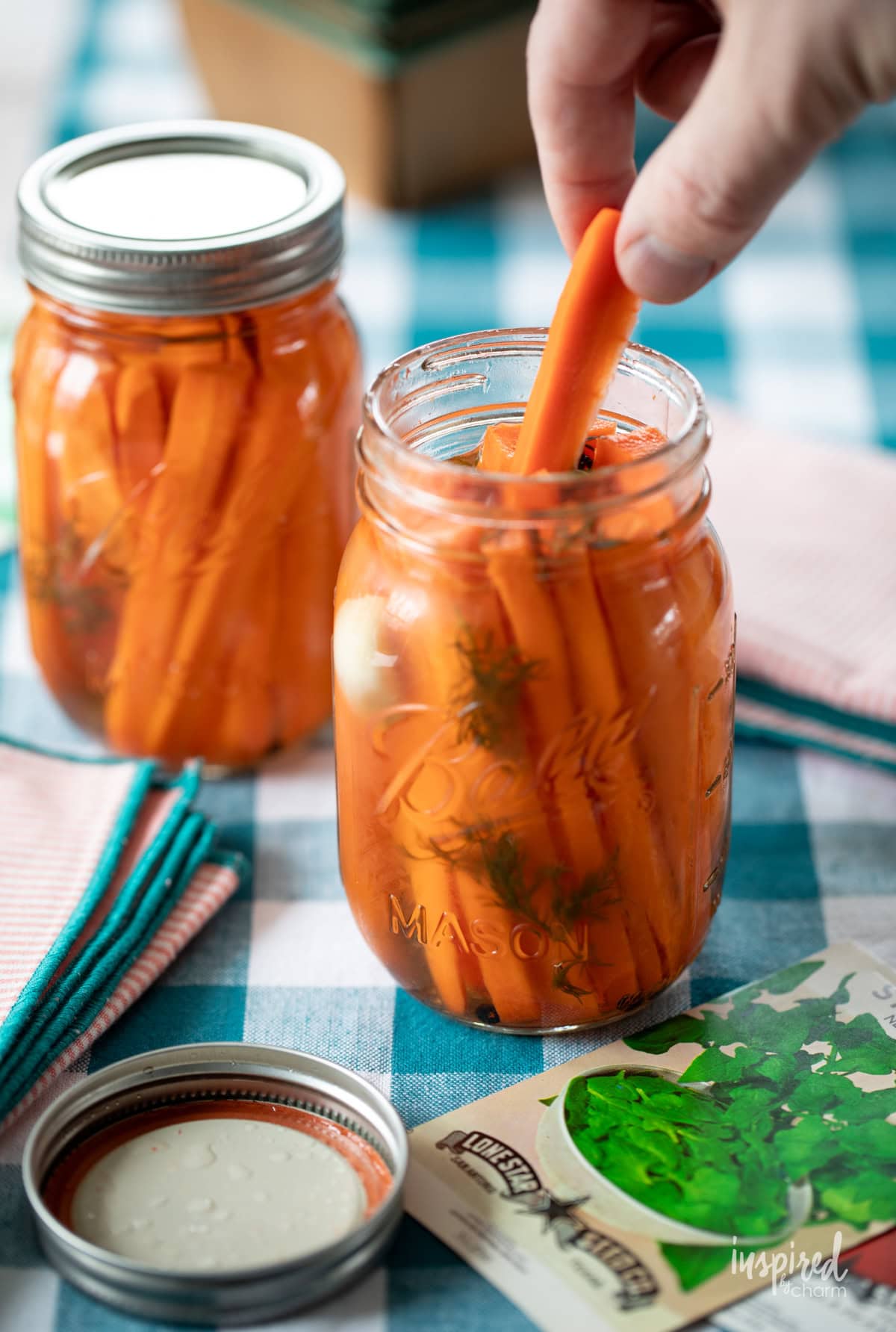 hand taking pickled carrots out of mason jar.