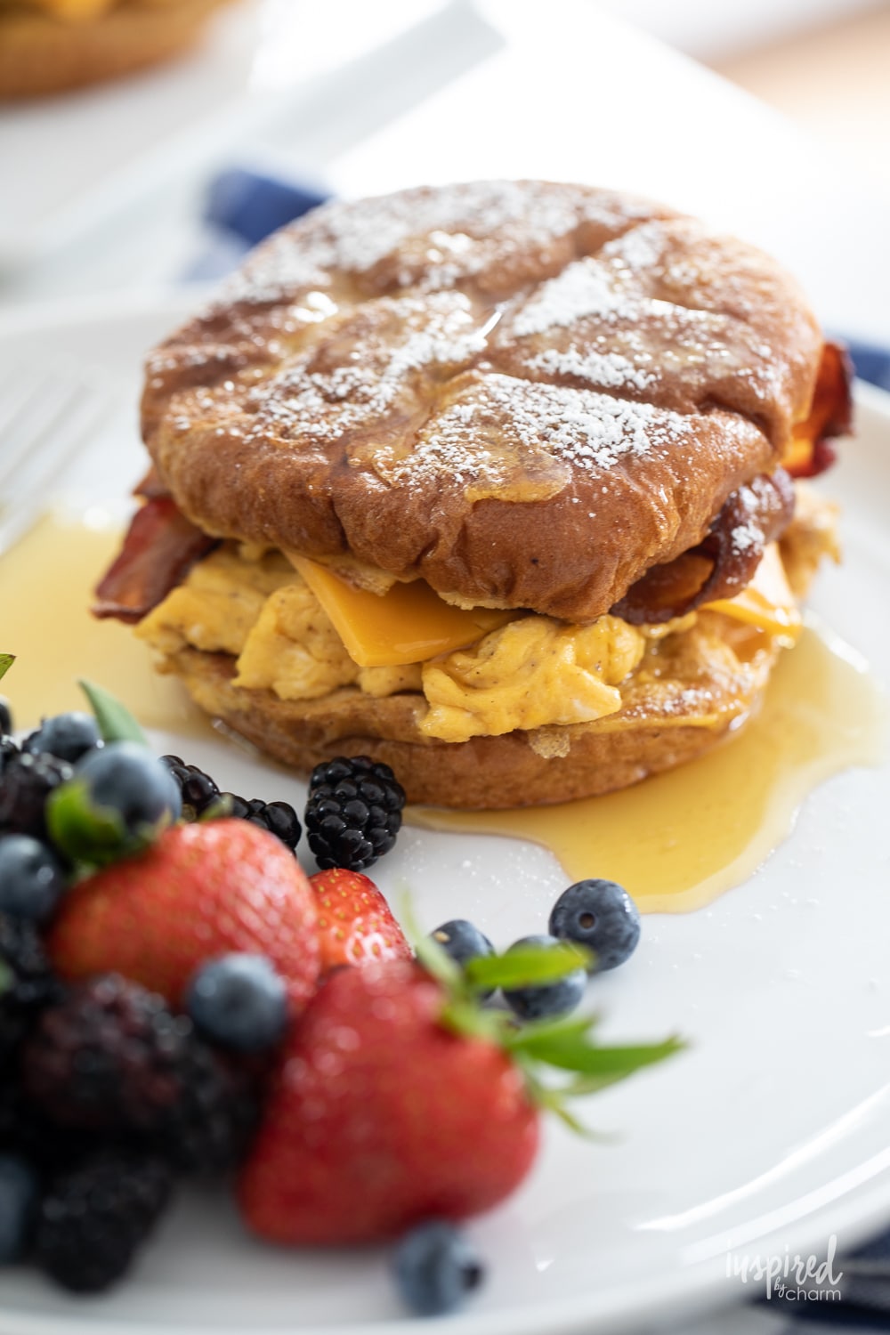 french toast breakfast sandwich on a plate with fresh berries.