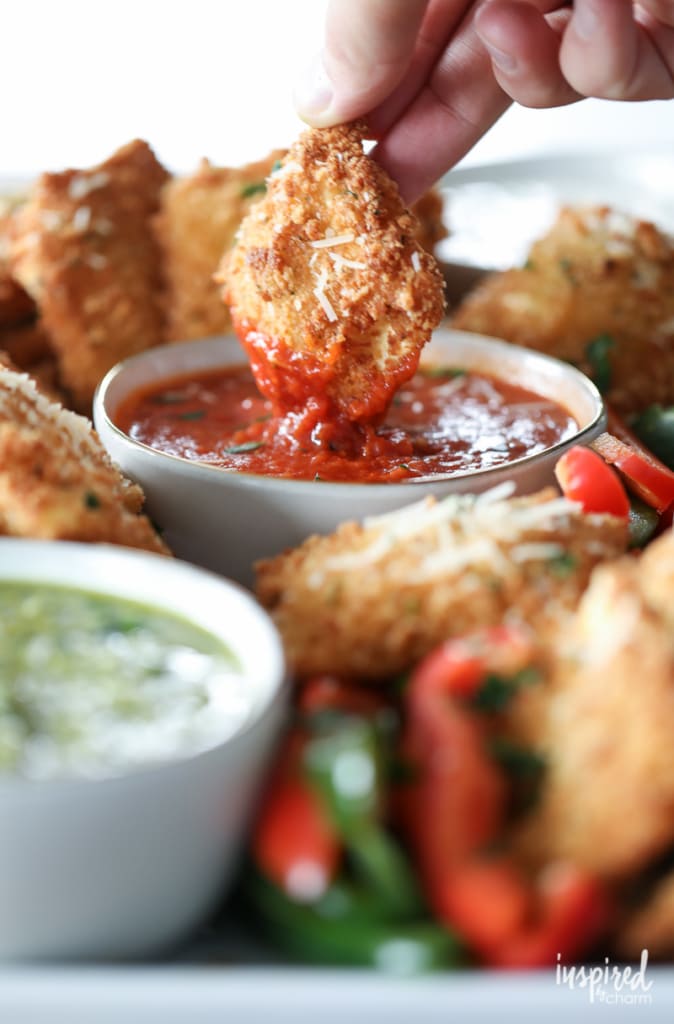 fried ravioli appetizer being dipped into marinara sauce