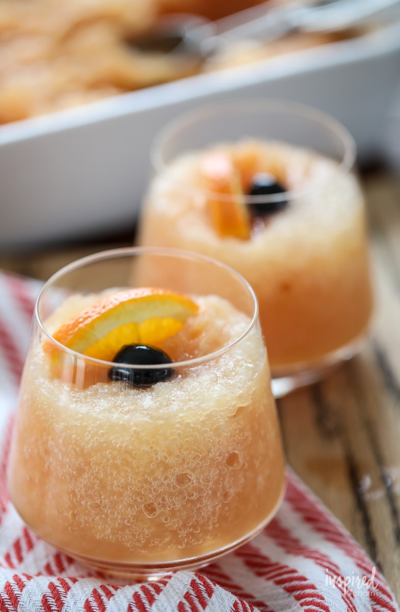 two Frozen Old Fashioned Slush garnished with cherry and orange slice. 