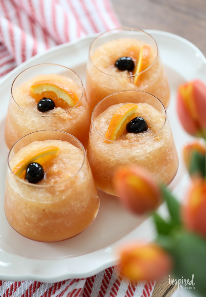 Frozen Old Fashioned Slush cocktails garnished with cherries and orange slices. 