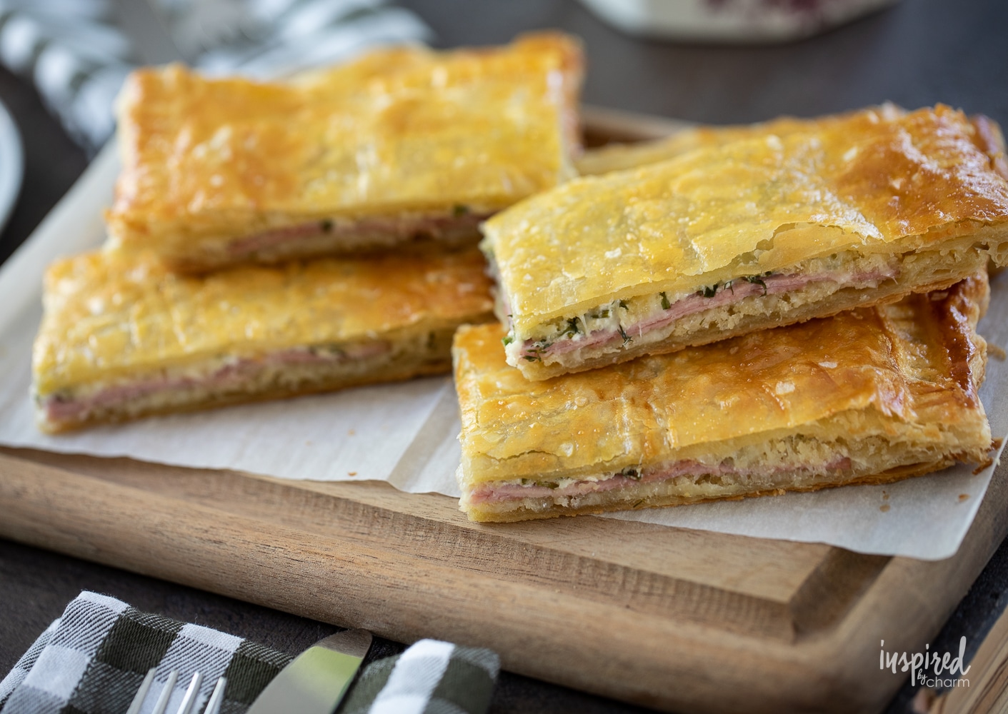 puff pastry ham sandwiches stacked and arranged on a cutting board.