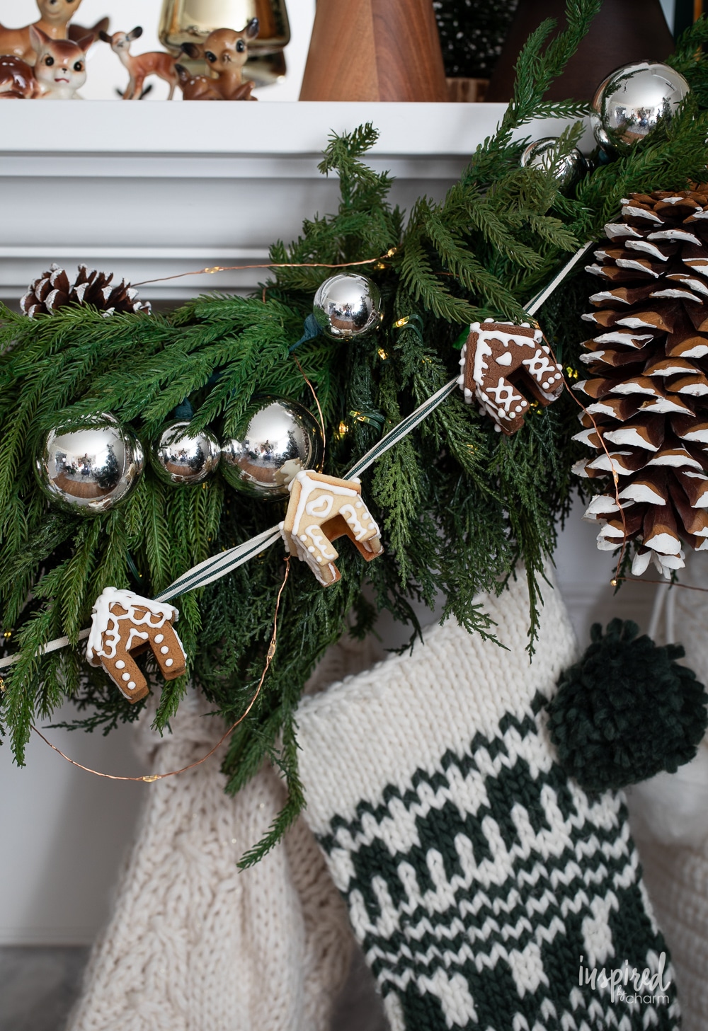 mini gingerbread house garland strung on a mantel with a pine garland.