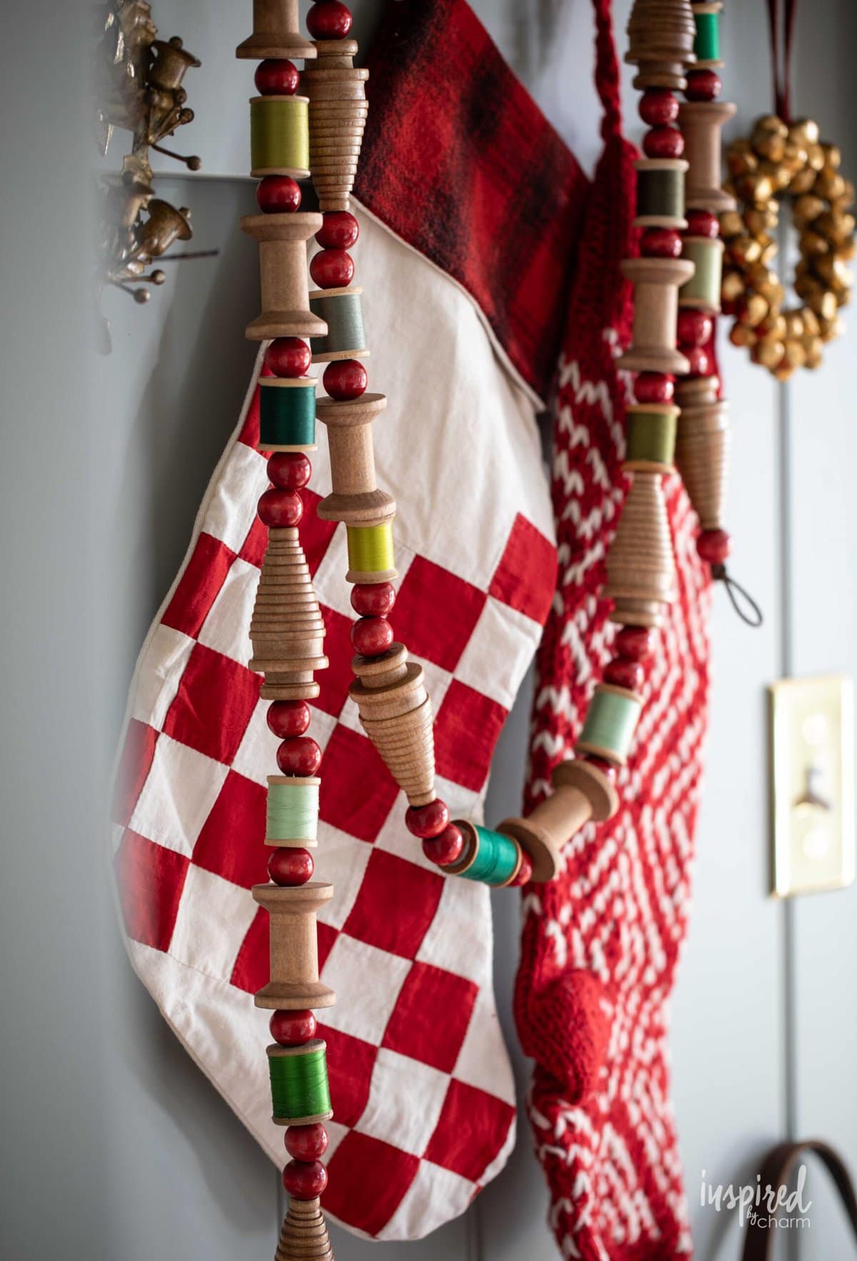 Vintage Bobbin Christmas Garland hung on peg hooks with stockings.