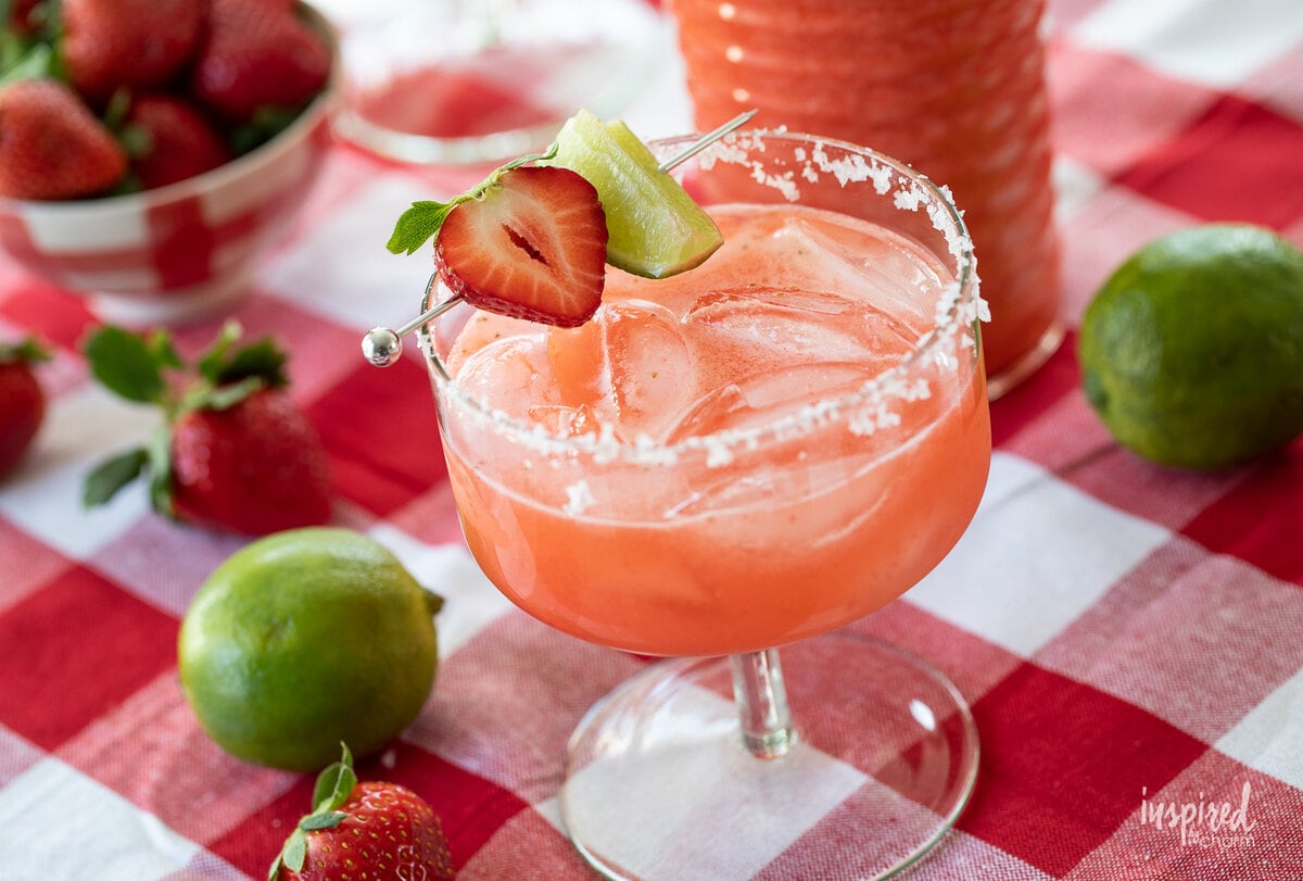 strawberry margarita in glass with strawberry and lime garnish.