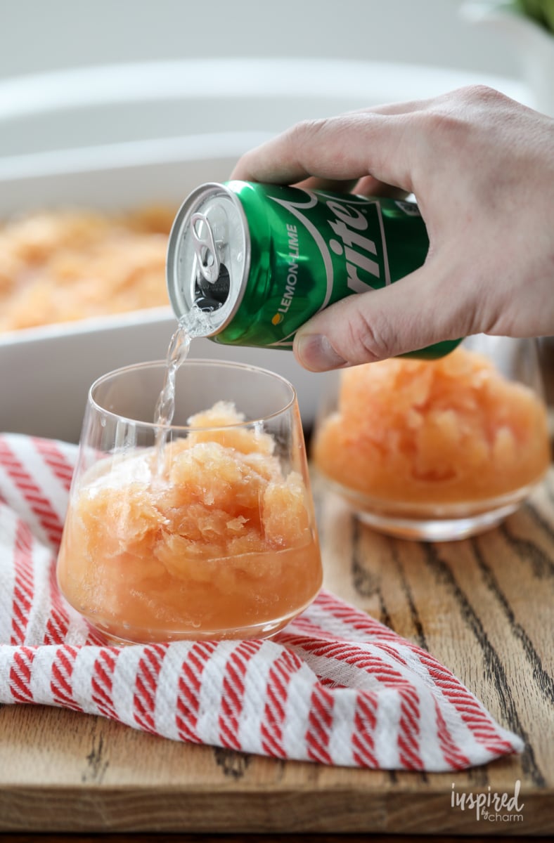 hand pouring lemon lime soda into glasses filled with Frozen Old Fashioned Slush. 