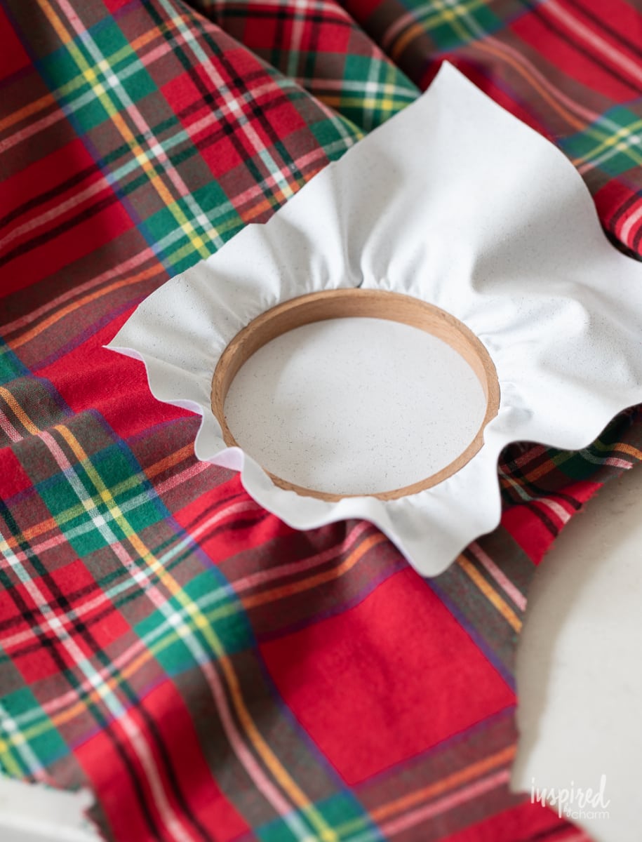 adding plaid fabric to embroidery hoop.