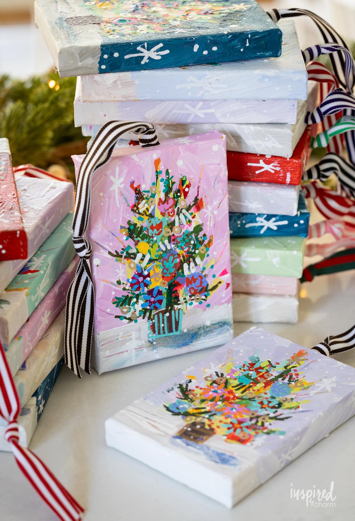 christmas tree painted on a small canvas with a ribbon attached.