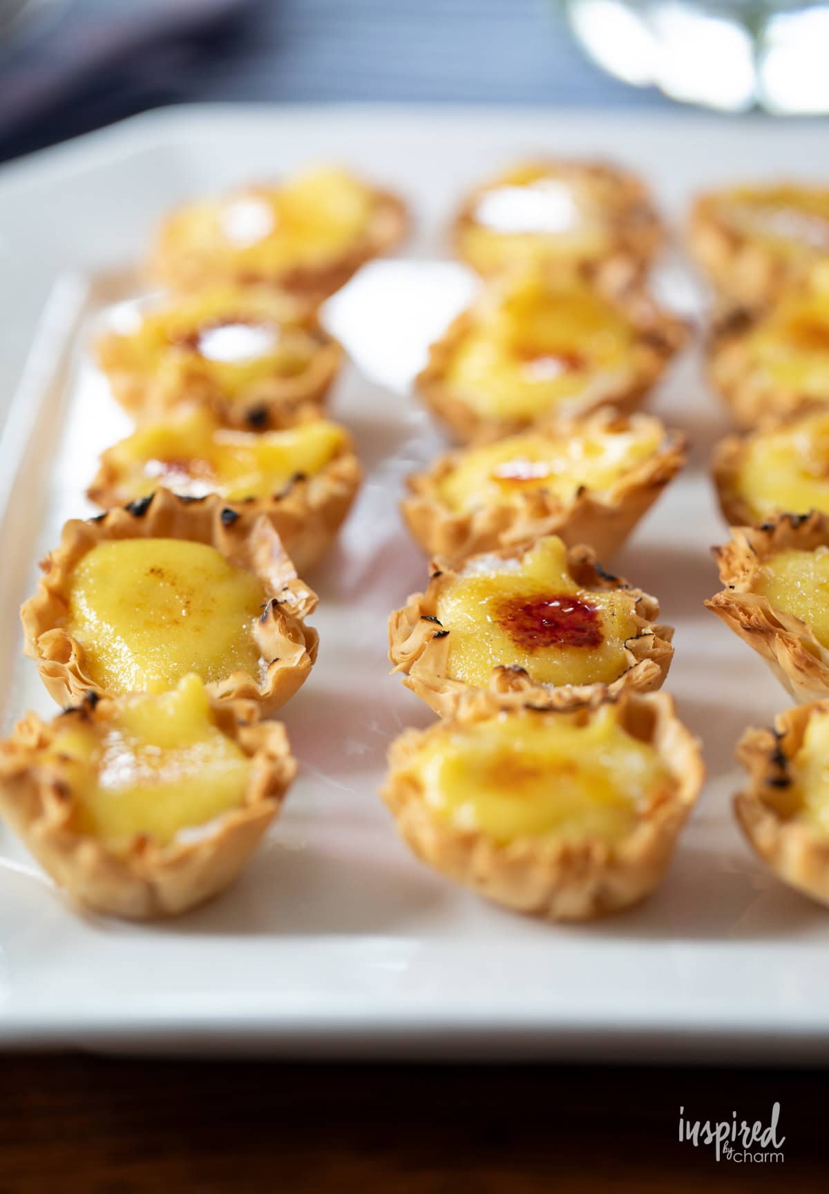 Crème Brûlée Tartlets arranged on a large white platter.