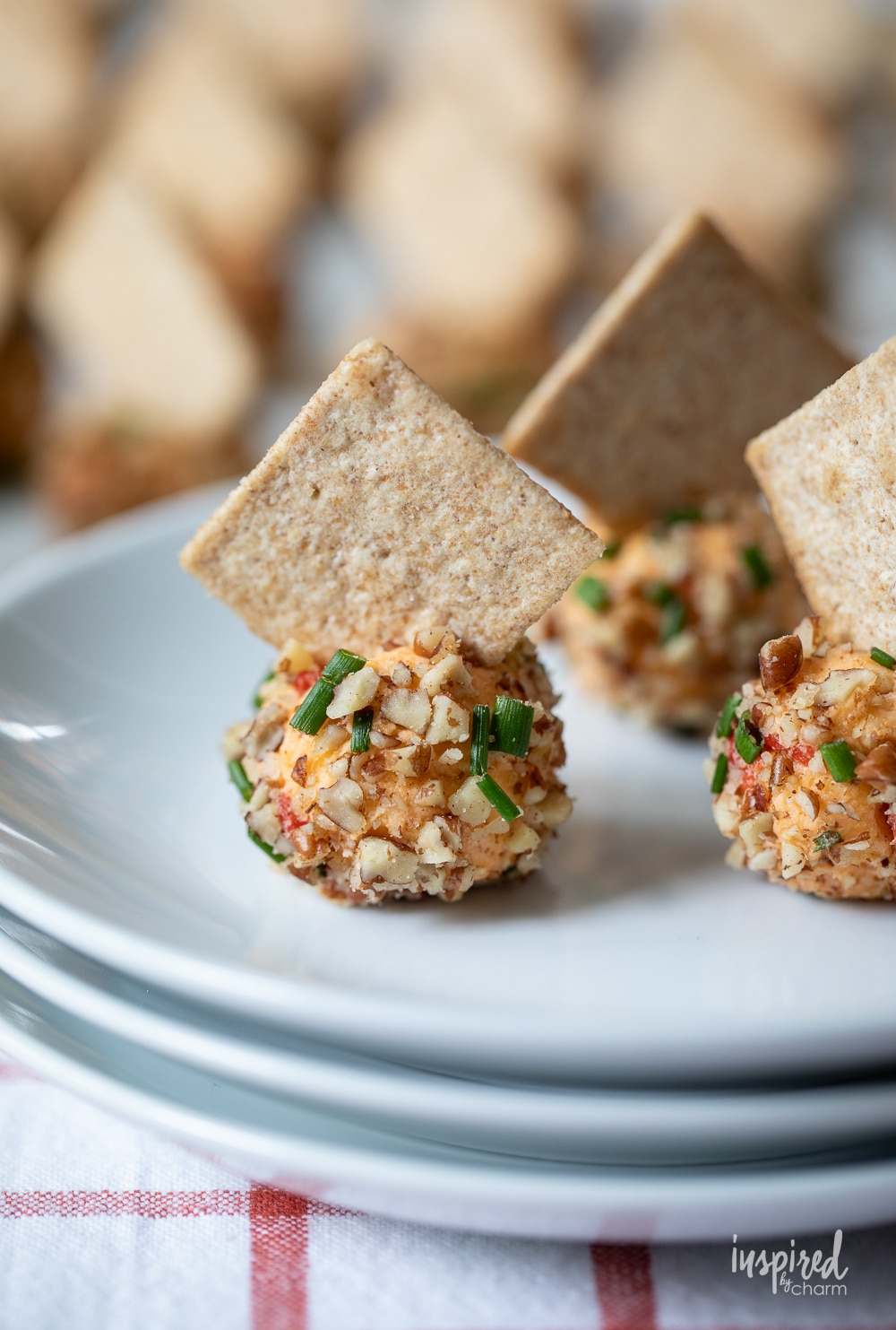 three adorable mini pimento cheese balls on white plates.