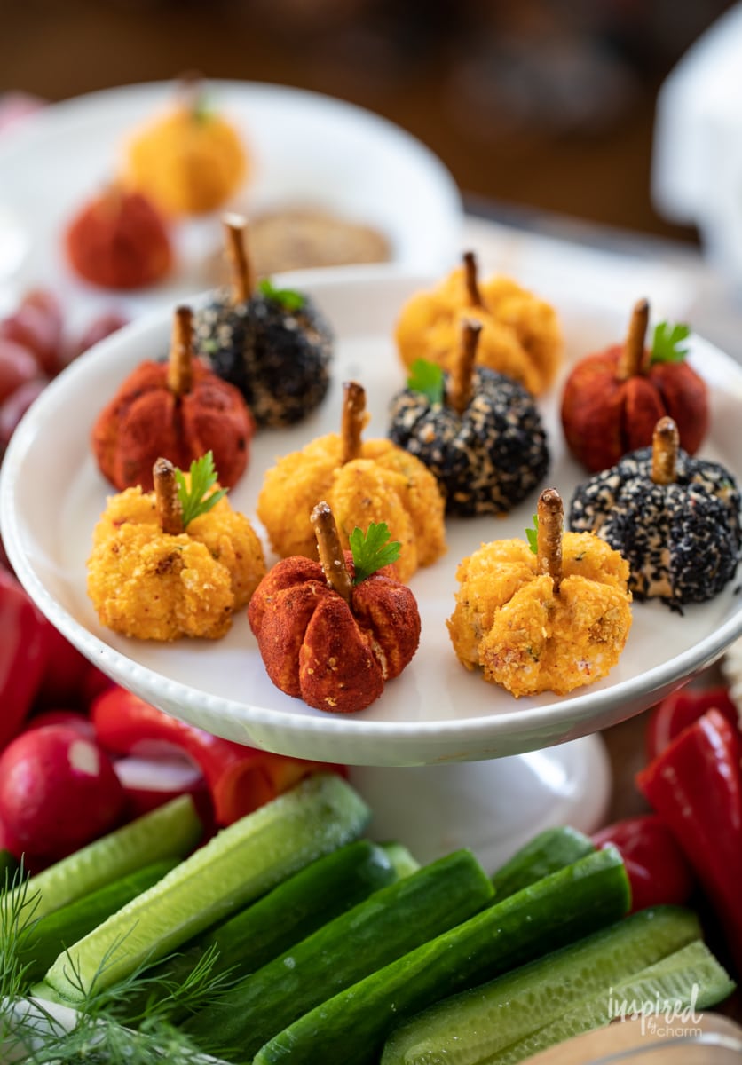 Mini Pumpkin Cheese Balls on a cake stand with vegetables.