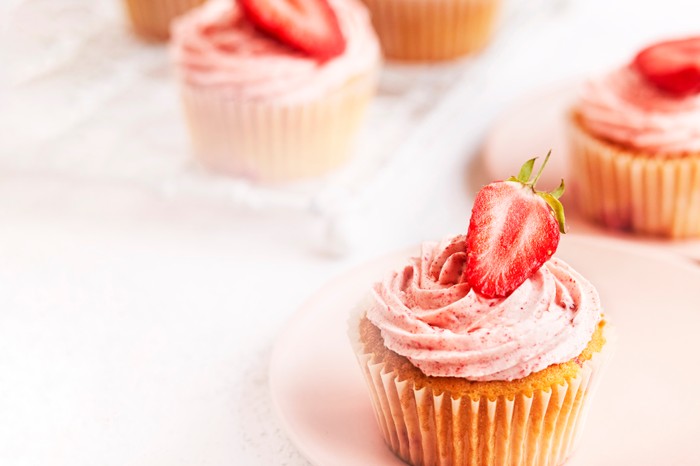 Cupcakes topped with frosting and sliced strawberries