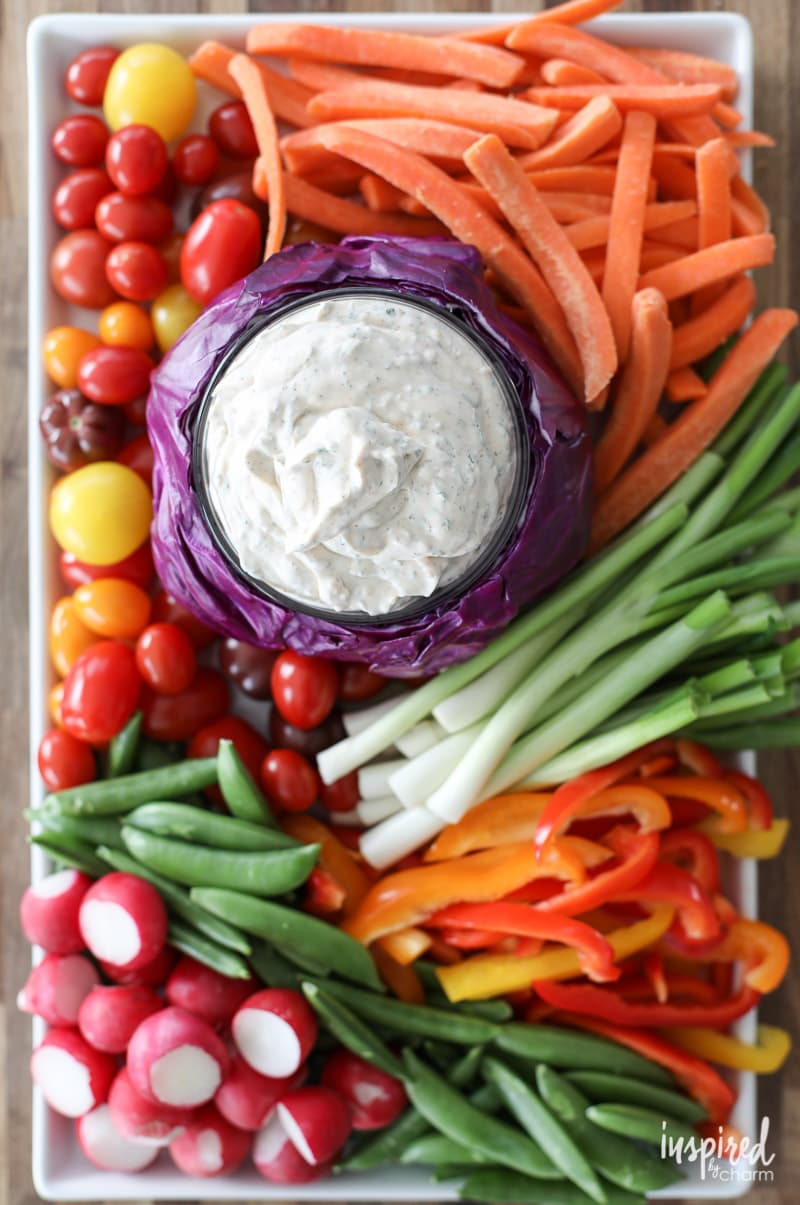 Really Good Veggie Dip served in a purple cabbage on a plate of vegetables.