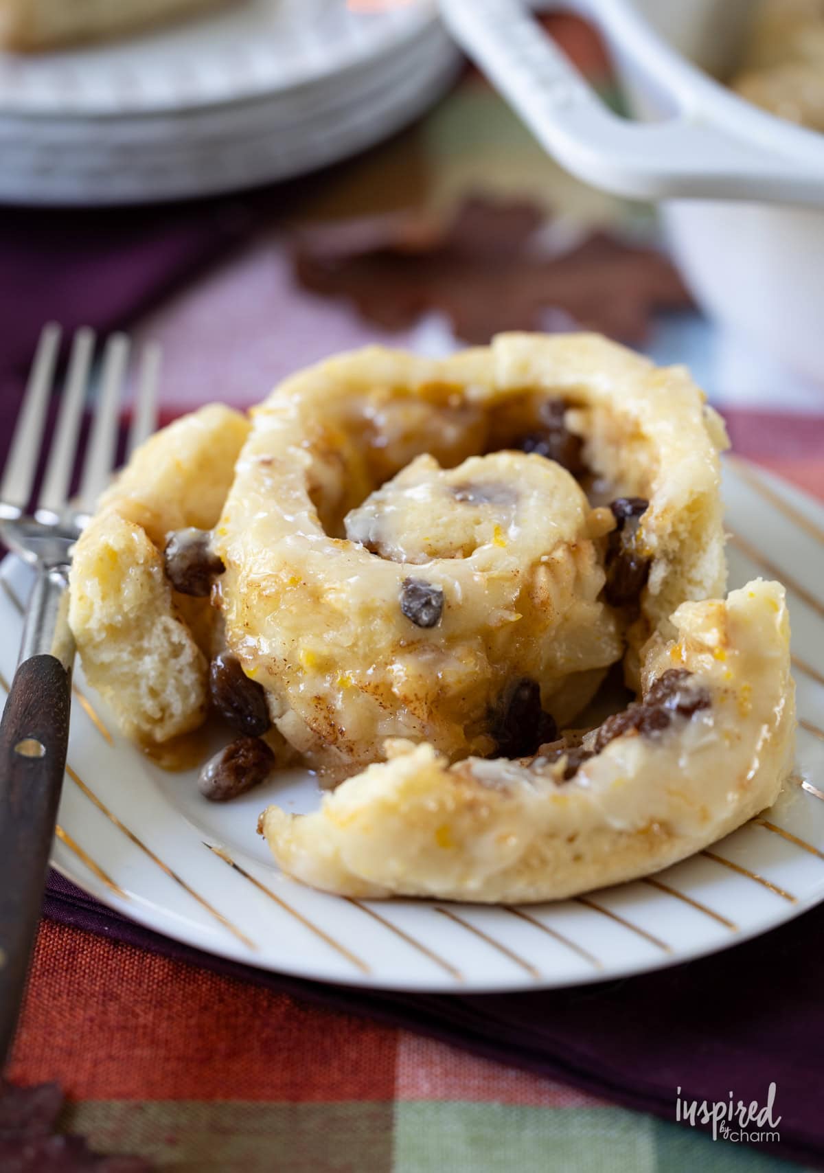 single Chelsea Bun with Pears and Raisins on a plate served with a fork.