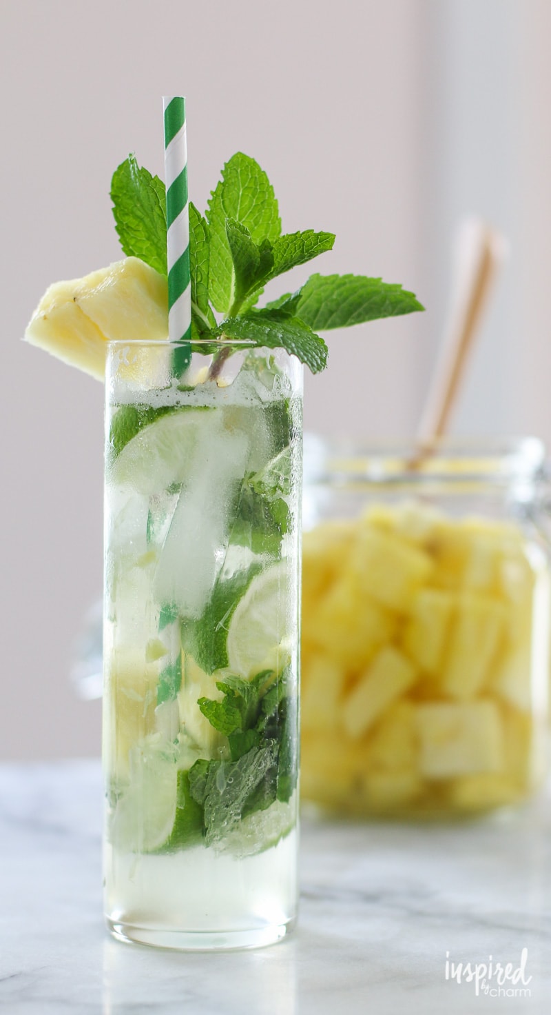 Pineapple Mojito in a glass with mint garnish and paper straw.