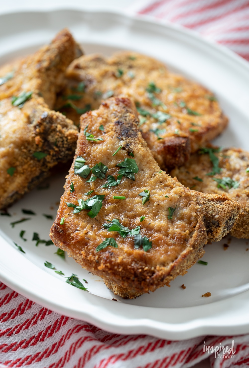 white platter with shake and bake pork chop sprinkled with fresh herbs.