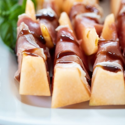 Prosciutto Melon Bites on white platter.