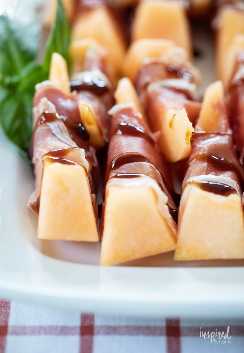 Prosciutto Melon Bites on white platter.