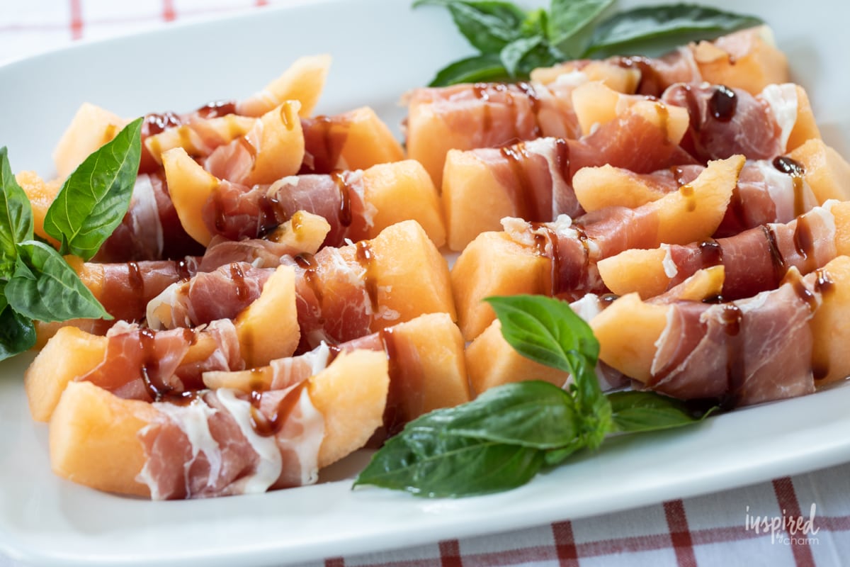 Prosciutto Melon Bites on white platter.
