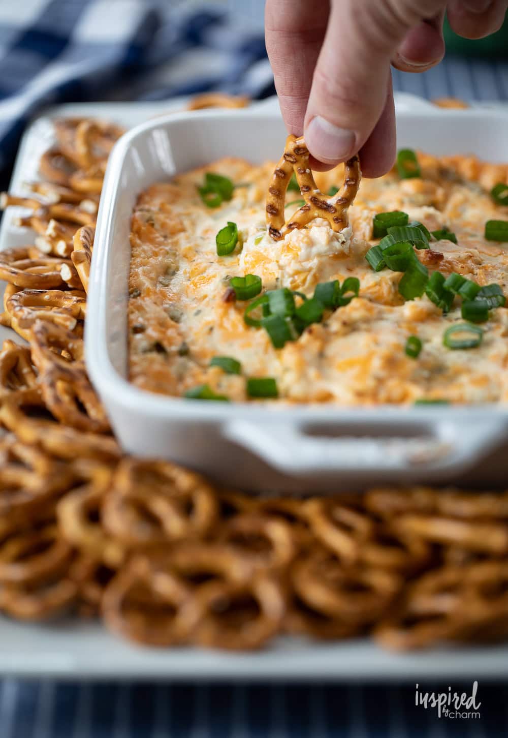 hand with pretzel dipping into pretzel dip.