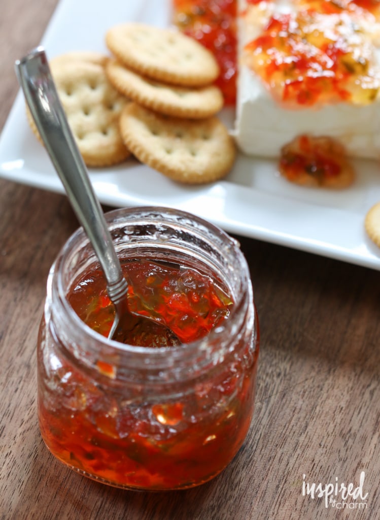 crackers and cream cheese behind an open jar of red pepper jelly